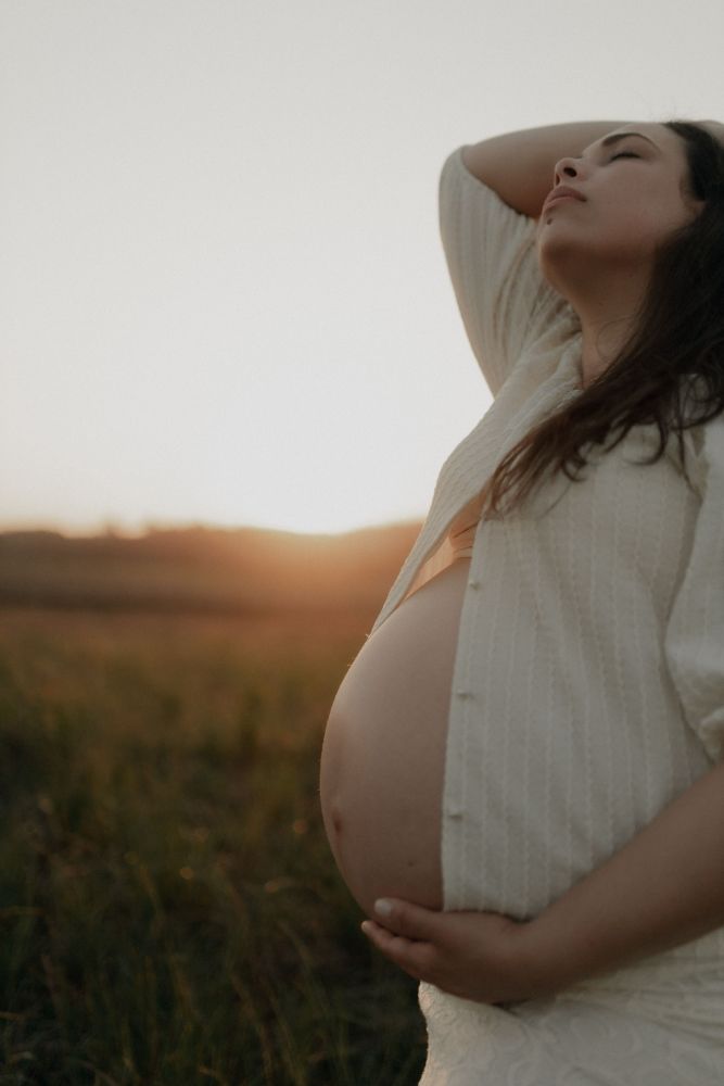 Une femme enceinte assise, les mains autour de son ventre