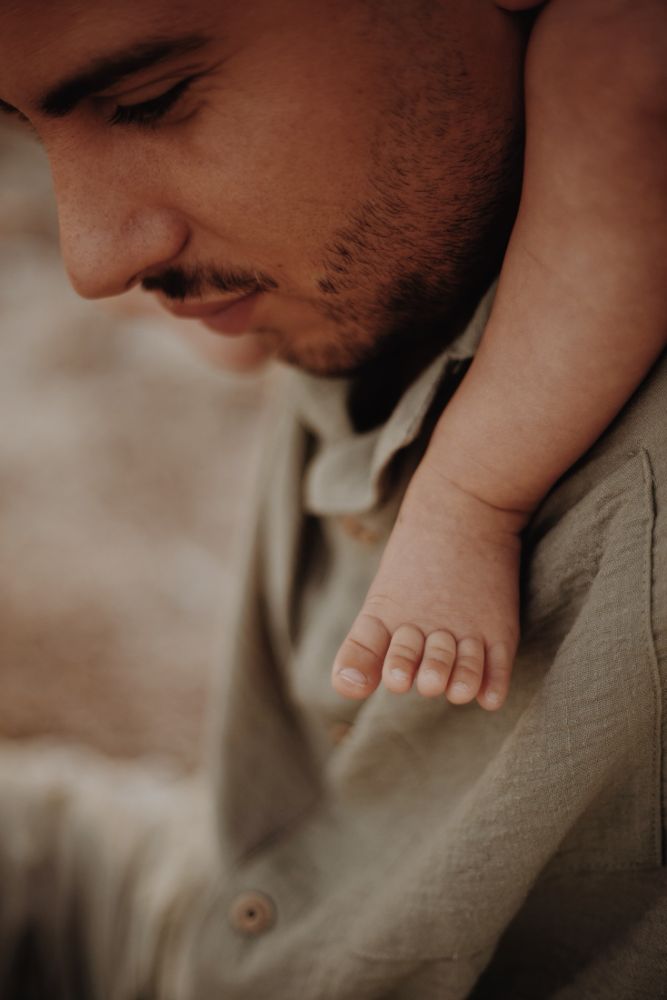 Pied de bébé posé dans la main de son père