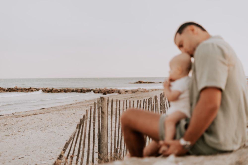Un père et son bébé assis face à la mer