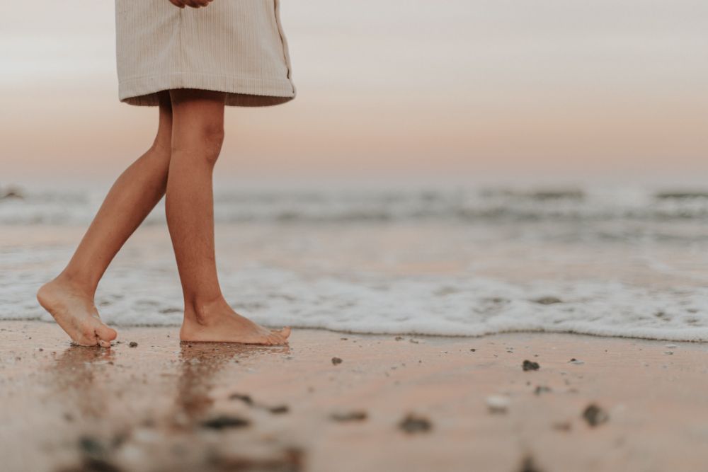 Jambes et pieds nus d'une enfant sur le sable mouillé