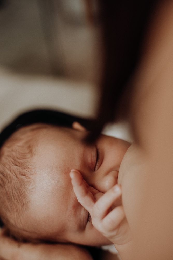 Bébé au sein, une petite main posée sur le visage