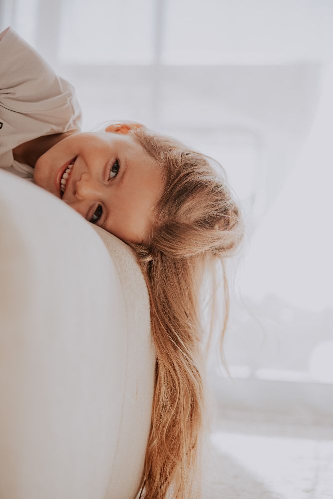 Une fillette souriante, la tête posée sur le canapé