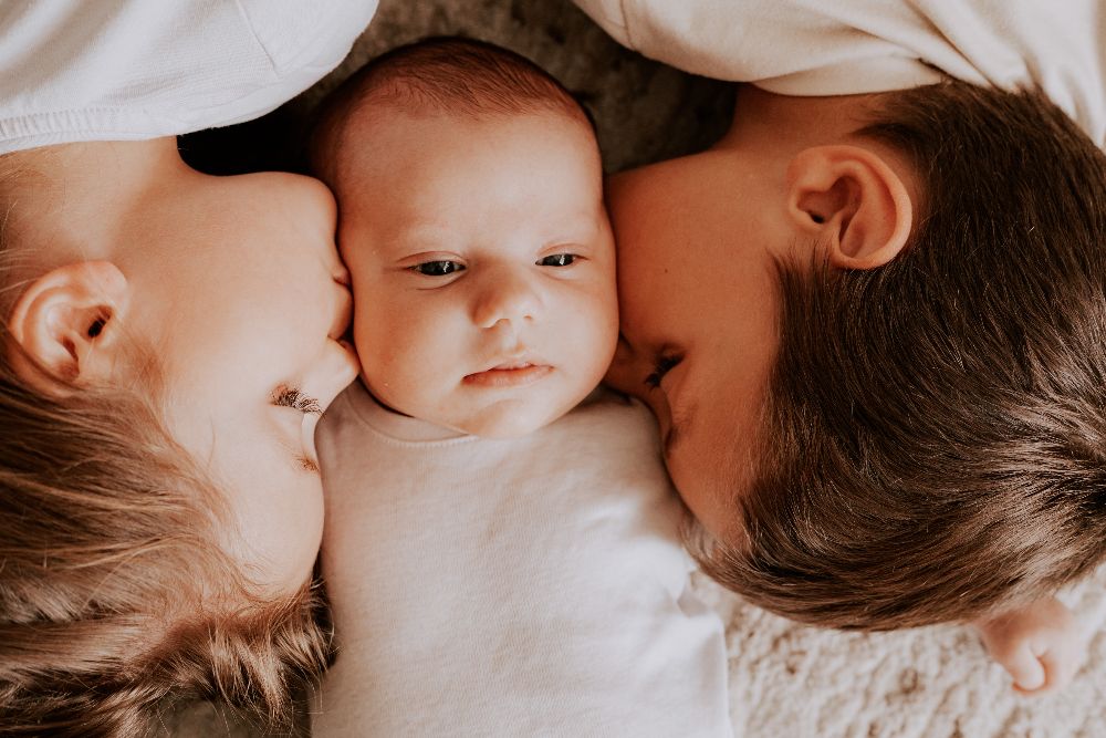 Un frère et une sœur embrassent leur petit frère